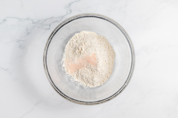 Image shows a glass bowl with flour and sea salt on top.