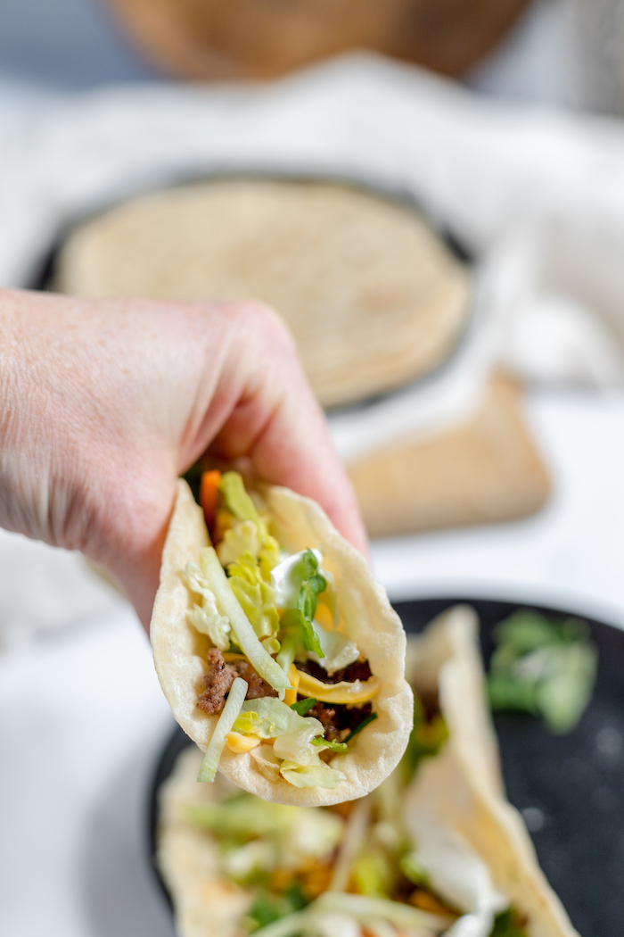 Image shows a hand holding a taco made using sourdough tortillas