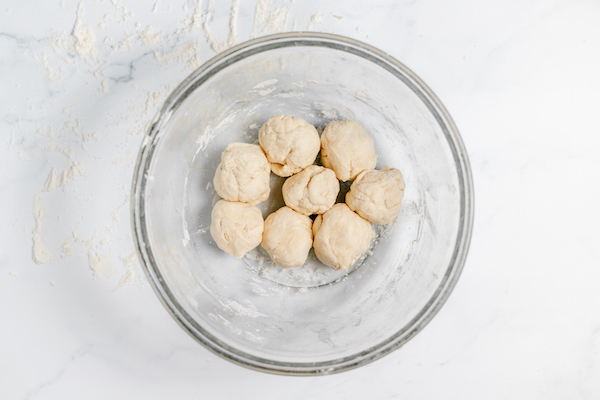 Image, taken from above shows balls of tortilla dough in a glass bowl ready to press