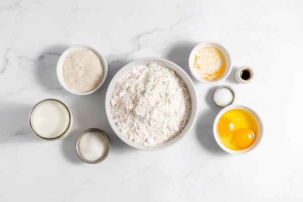 Image, taken from above shows several bowls of ingredients for making sourdough waffles