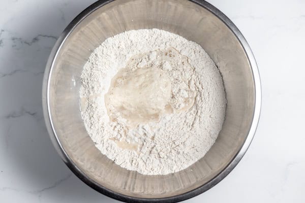 Image, taken from above, shows flour, salt, sourdough starter in a large mixing bowl