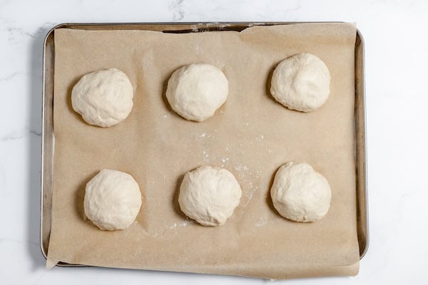 Image, taken from above, shows 6 sourdough buns on pan ready to rise