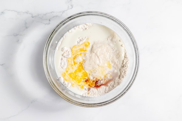 Image, taken from above, shows a bowl of butter, milk, flour, sourdough starter in a bowl.