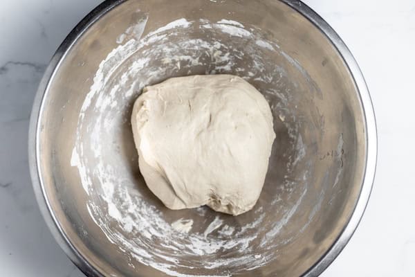 Image, taken from above, shows a sourdough ball in a large mixing bowl ready for bulk fermentation