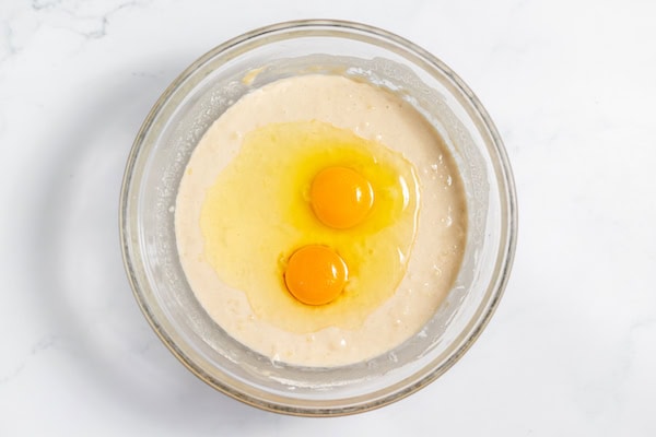 Image, taken from above shows a glass bowl with eggs in waffle batter after it's fermented.