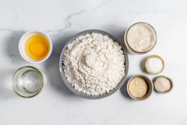 Image, taken from above, shows bowls with the ingredients for making sourdough hamburger buns