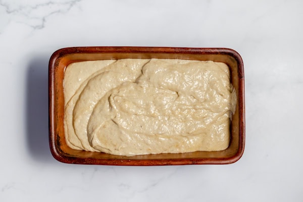 Image, taken from above shows sourdough banana bread batter in loaf pan
