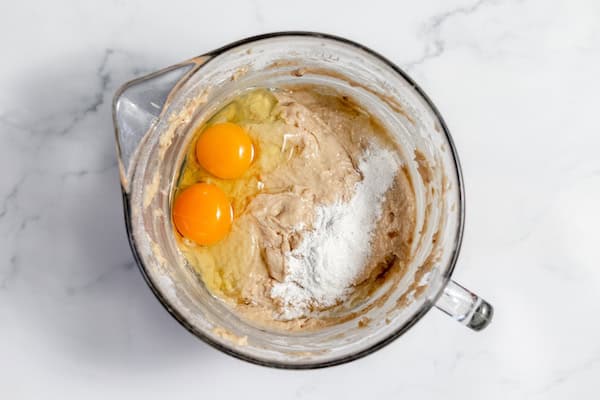 Image, taken from above shows eggs and salt added to sourdough batter in a large mixing bowl