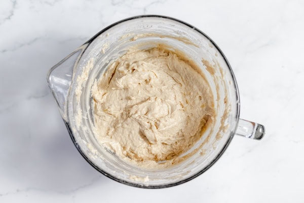 Image, taken from above shows the mixed ingredients for the sourdough banana bread in a large glass mixing bowl.