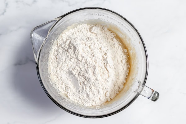 Image, taken from above shows flour on top of a bowl of banana bread ingredients