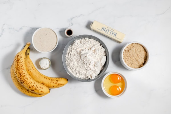 Image, taken from above show sourdough banana bread ingredients on a counter in small bowls. 