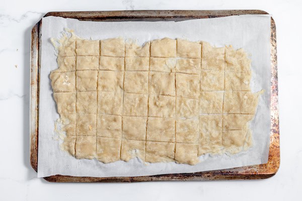 Image, taken from above shows scored crackers on a baking sheet