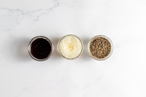 Image, taken from above, shows several small containers with the ingredients for making comfrey salve on a table