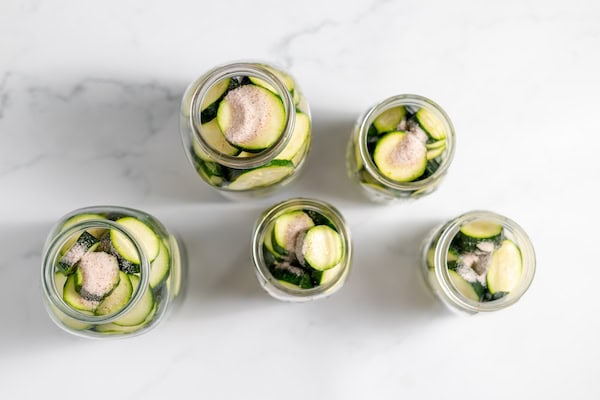 canning jars packed with zucchini and topped with salt