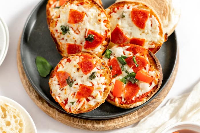 mini pizzas made with english muffins on a plate.