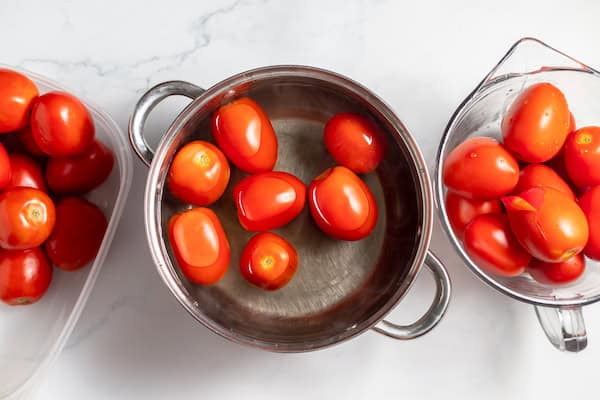 Image, taken from above, shows blanched tomatoes in hot water to make them easy to peel