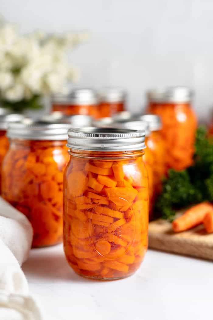 canning carrots in pint jars with flowers in the background