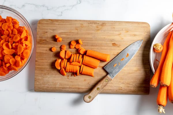 chopping carrots on a wooden cutting board