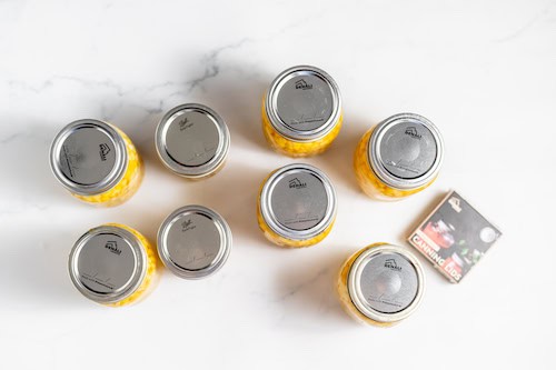 canning jars filled with corn on a table