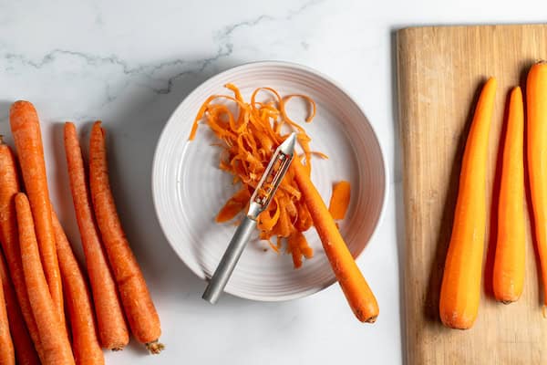 peeling carrots with a peeler, and knife