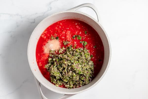 Image, taken from above shows salsa ingredients in a white pan sitting on a counter.