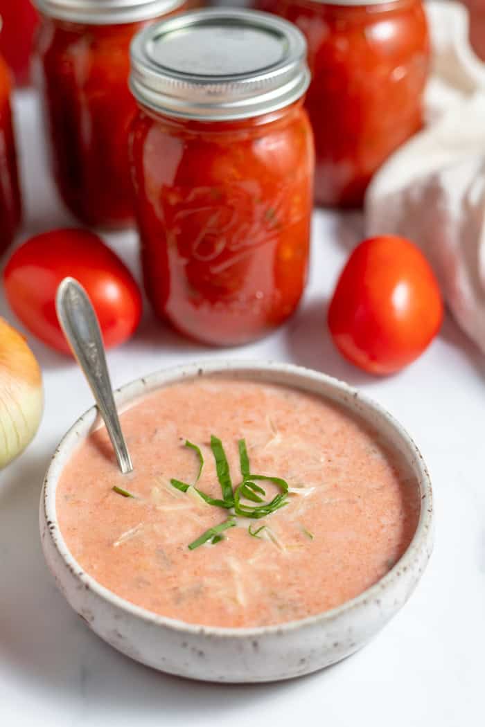 bowl of prepared tomato soup with jars in background