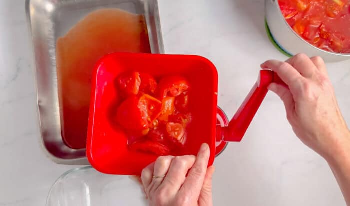 straining tomatoes through a fruit strainer