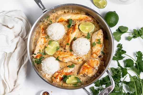 skillet of chicken, rice, and lime wedges