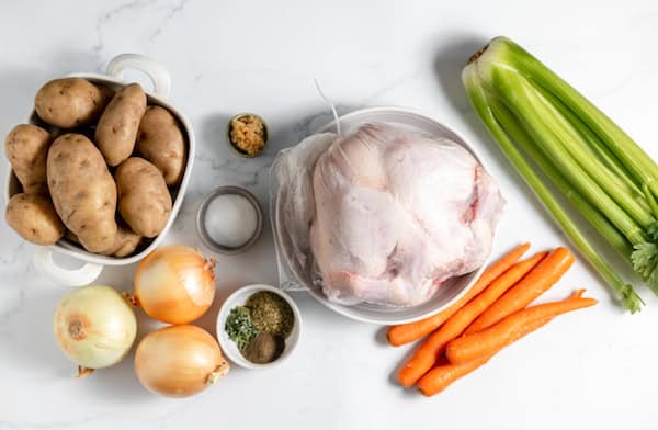 Image, taken from above, shows the ingredients needed to make chicken soup laid out on a counter. 