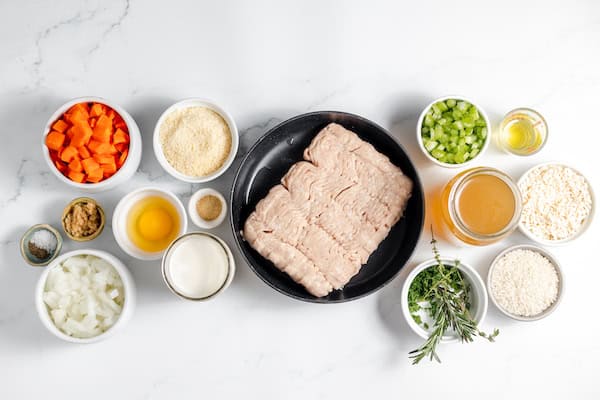 Image, taken from above, shows the ingredients to make chicken meatball soup lined up on a table.