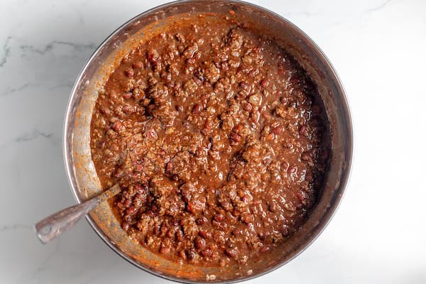 Image, taken from above, shows a large bowl of chili ready to ladle into canning jars