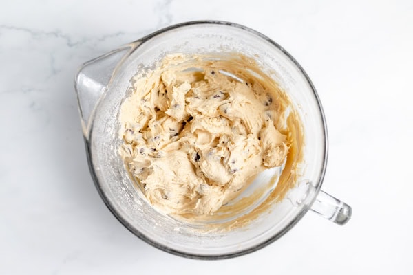 Image, taken from above shows chocolate chip sourdough cookie dough in a large glass mixing bowl.