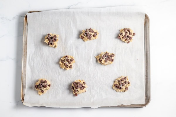 Image, taken from above shows cookie dough rolled into balls on a baking sheet.