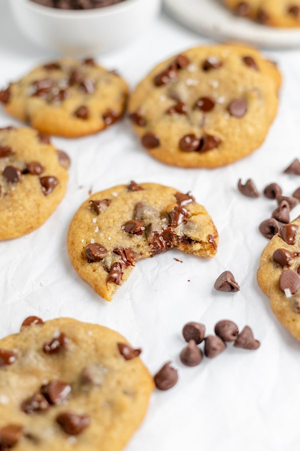Image shows several sourdough chocolate chip cookies, one with a bite out of it in the center.