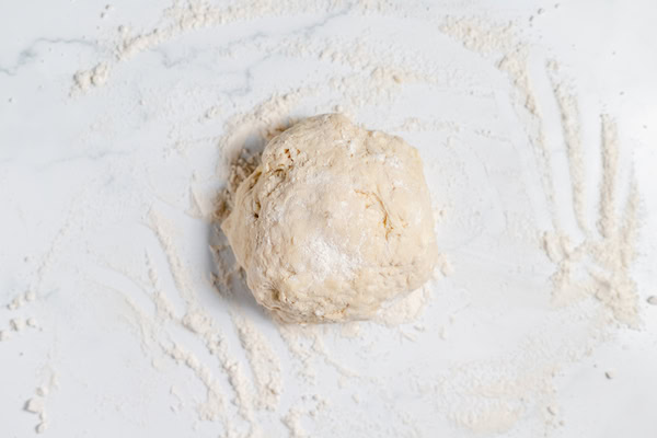 Image, taken from above, shows a ball of sourdough pie crust ready to roll out.