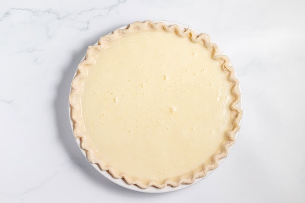 Image, taken from above, shows an unbaked lemon buttermilk pie in the pie crust. 