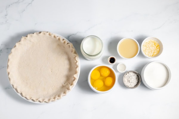Image, taken from above, shows a gluten free pie crust in a pie dish and small bowls of the ingredients for buttermilk lemon pie.