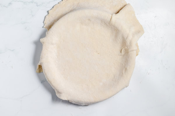 Image, taken from above, shows pie crust draped over pie pan before it's been trimmed. 