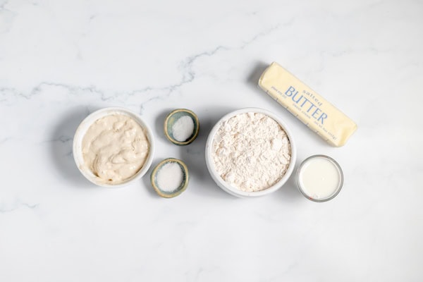 Image, taken from above, shows small bowls with the ingredients for making sourdough pie crust