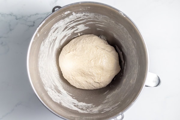 Image, taken from above shows a large sourdough ball in bowl after kneading.