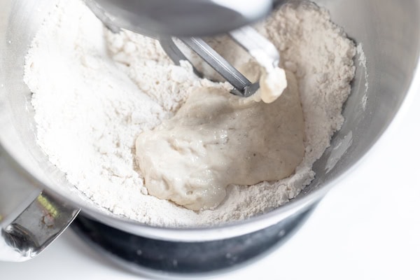 Image shows a large stand mixer with sourdough starter in a flour mixture.
