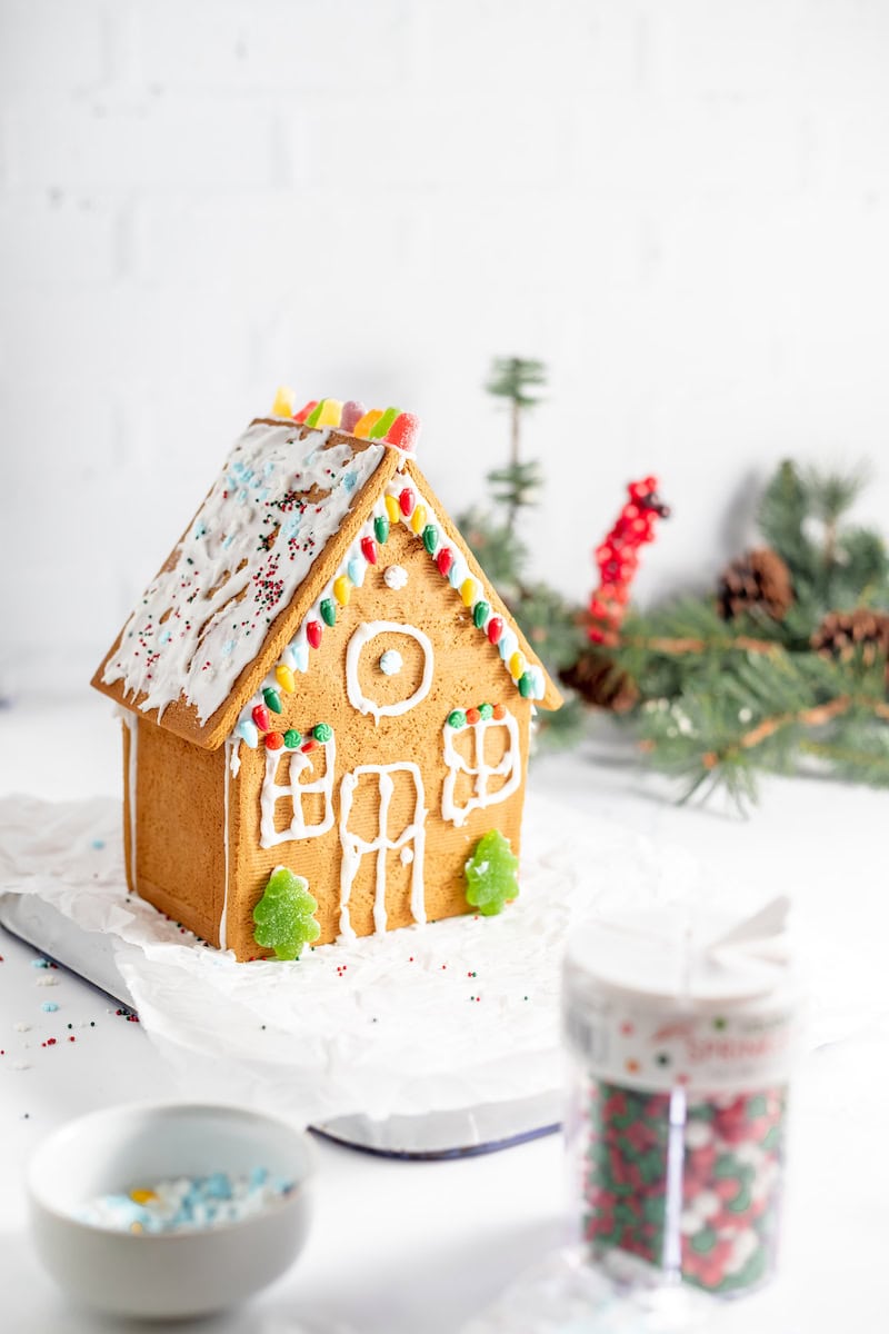 Image shows a fully decorated a gluten free gingerbread house on a table.