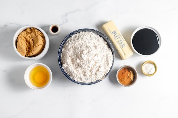 Image, taken from above, shows the ingredients for making a gluten free gingerbread house in bowls on a counter top