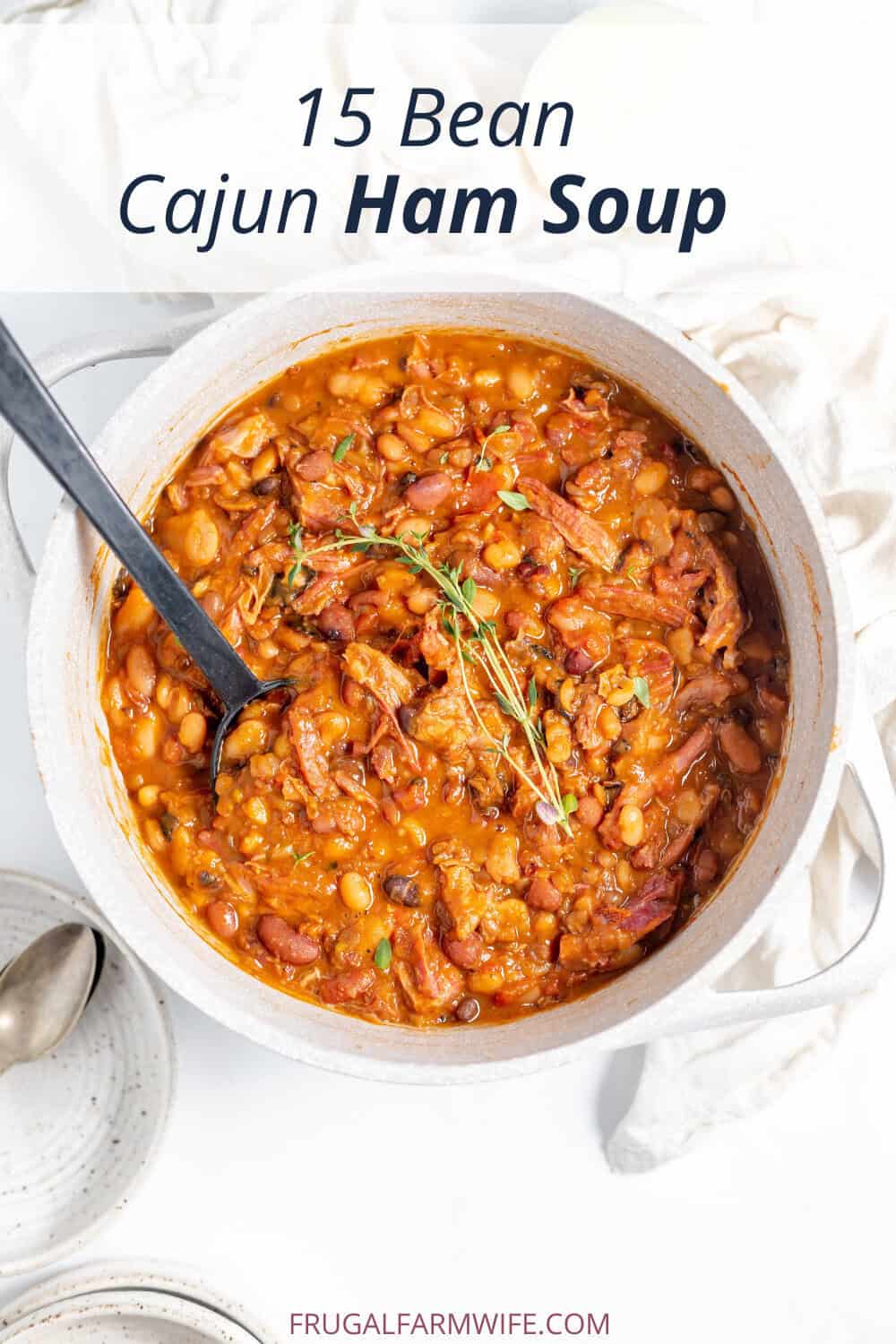 Image, taken from above, shows a large crock of 15 Bean Cajun Ham Soup with a ladle in it. 