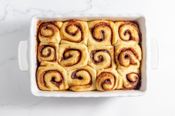 Image, taken from above, shows a pan of baked sourdough cinnamon rolls