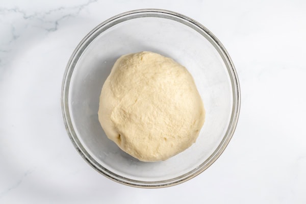 Image, taken from above, shows the ball of dough in a glass bowl.
