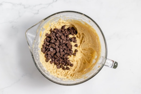Image, taken from above, shows a mixing bowl where chocolate chips have been added to banana bar batter.