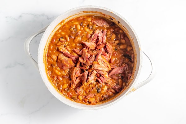 Image, taken from above, shows the ham added back into 15 bean soup in a large pot.