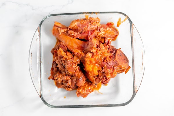 Image, taken from above, shows the hamhock removed from soup, ready to debone meat in a glass casserole dish.