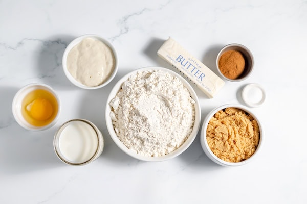 Image, taken from above shows the ingredients for making sourdough cinnamon rolls on a table.